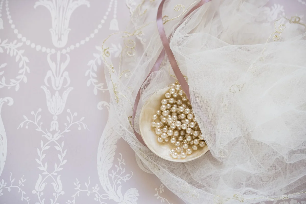 Close-up of coquette styling details: pink ribbon, lace trim, and pearl accessories