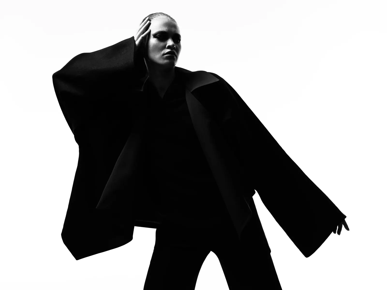 Woman in an oversized black jacket photographed in high-contrast silhouette, showing the long, sharp lines the Kibbe system calls yang