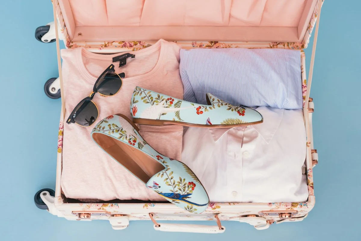 Clothing items and a pair of shoes packed in an open suitcase