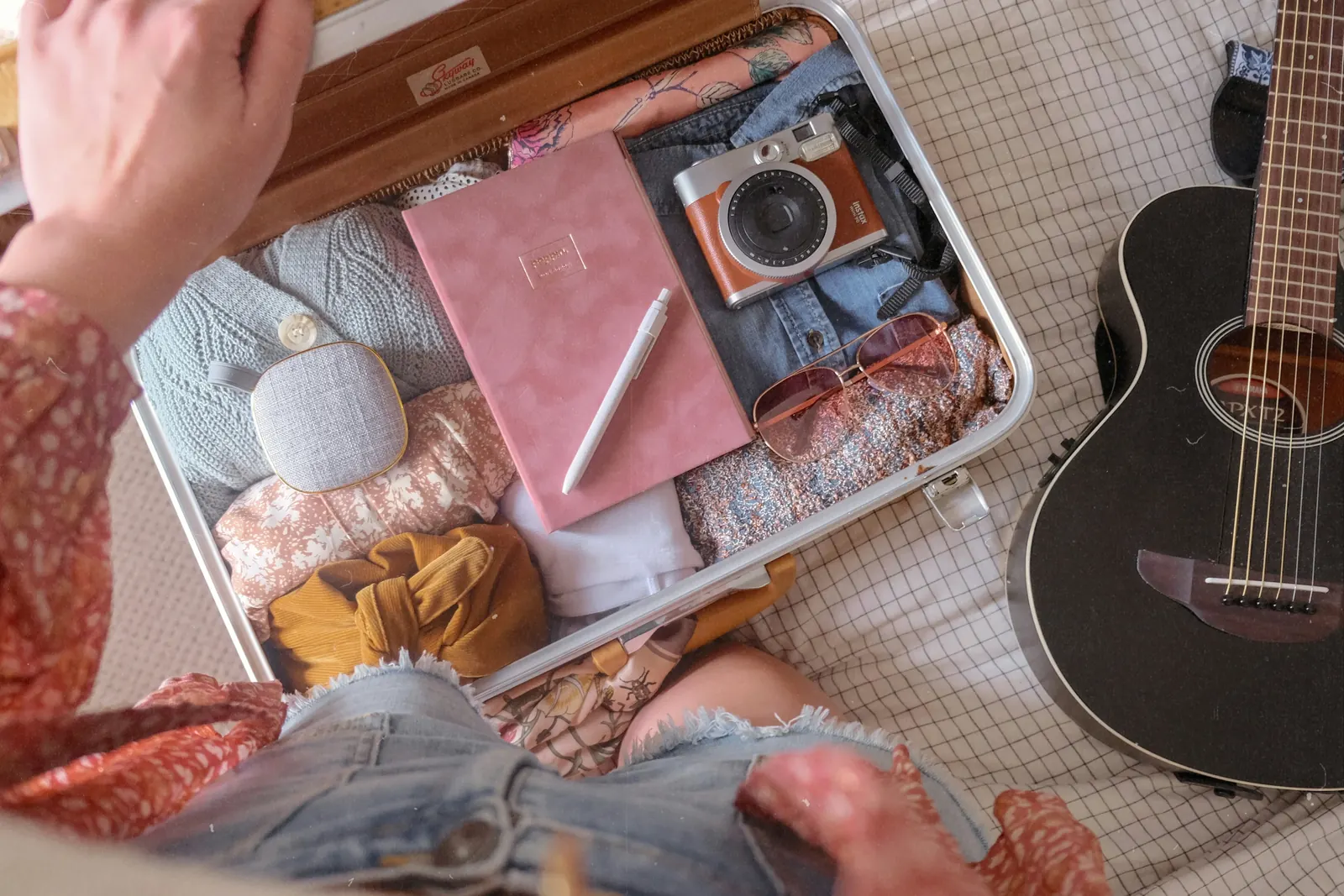 Woman packing a carry-on suitcase with a coordinated travel capsule wardrobe