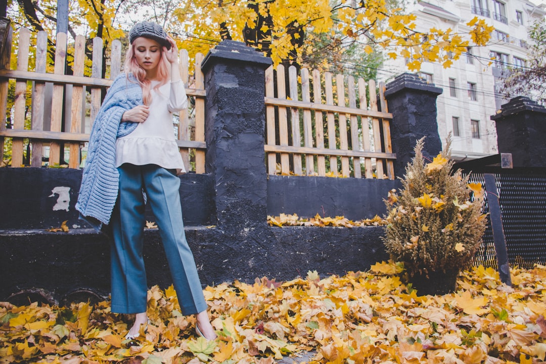 Woman in autumn layers walking through fallen leaves