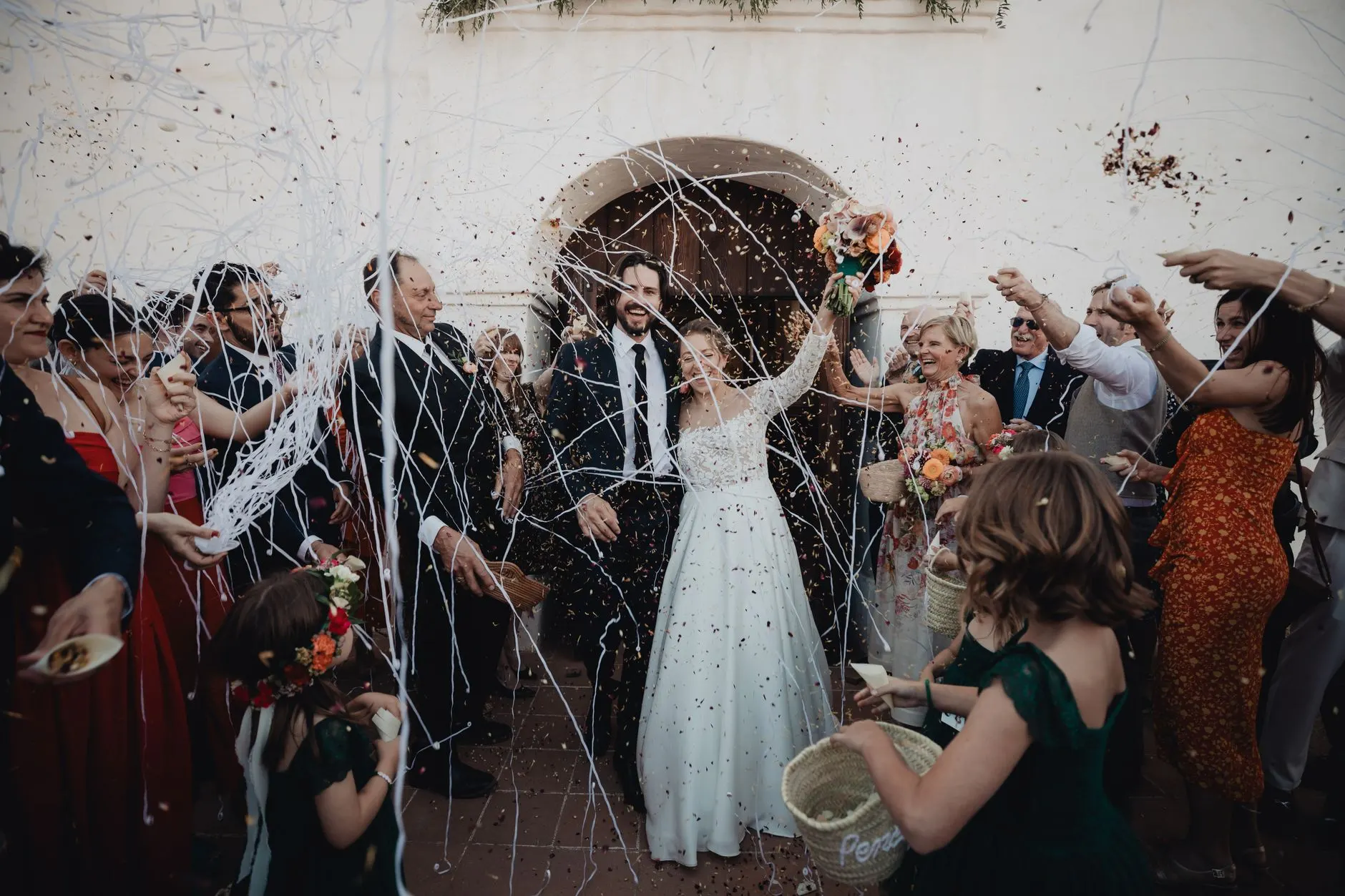 Wedding guests in colorful dresses and suits celebrating during the ceremony